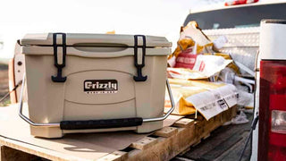 american farmer using a tan grizzly 20 cooler sitting on pallet in back of truck surrounded by corn seed bags